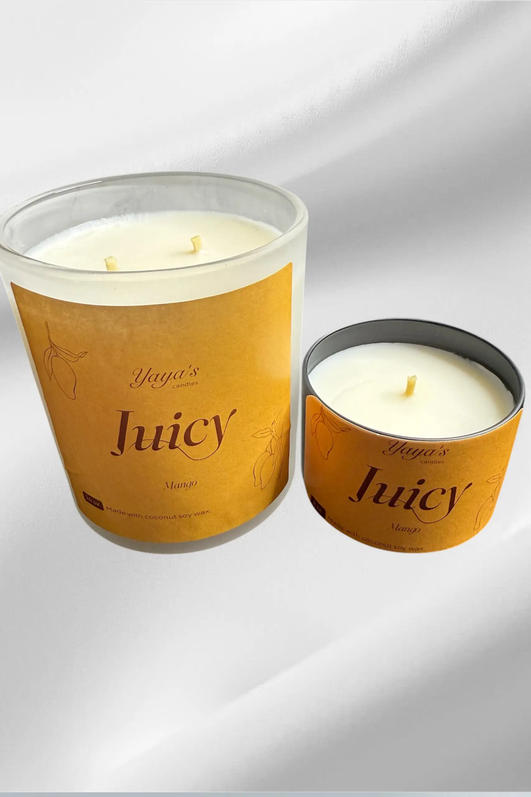 About-section-big-image-pt webp Two mango-scented candles from Yaya's Candles, featuring a large glass jar with two wicks and a small metal tin.Two mango-scented candles from Yaya's Candles, featuring a large glass jar with two wicks and a small metal tin.