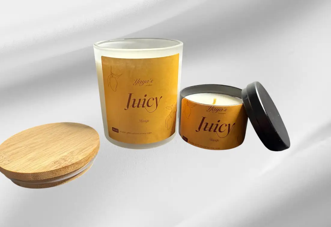 mango-product-images-for-front-end Two scented candles labeled "Juicy Mango" with a bamboo lid and a metal tin, showcasing their vibrant yellow packaging.