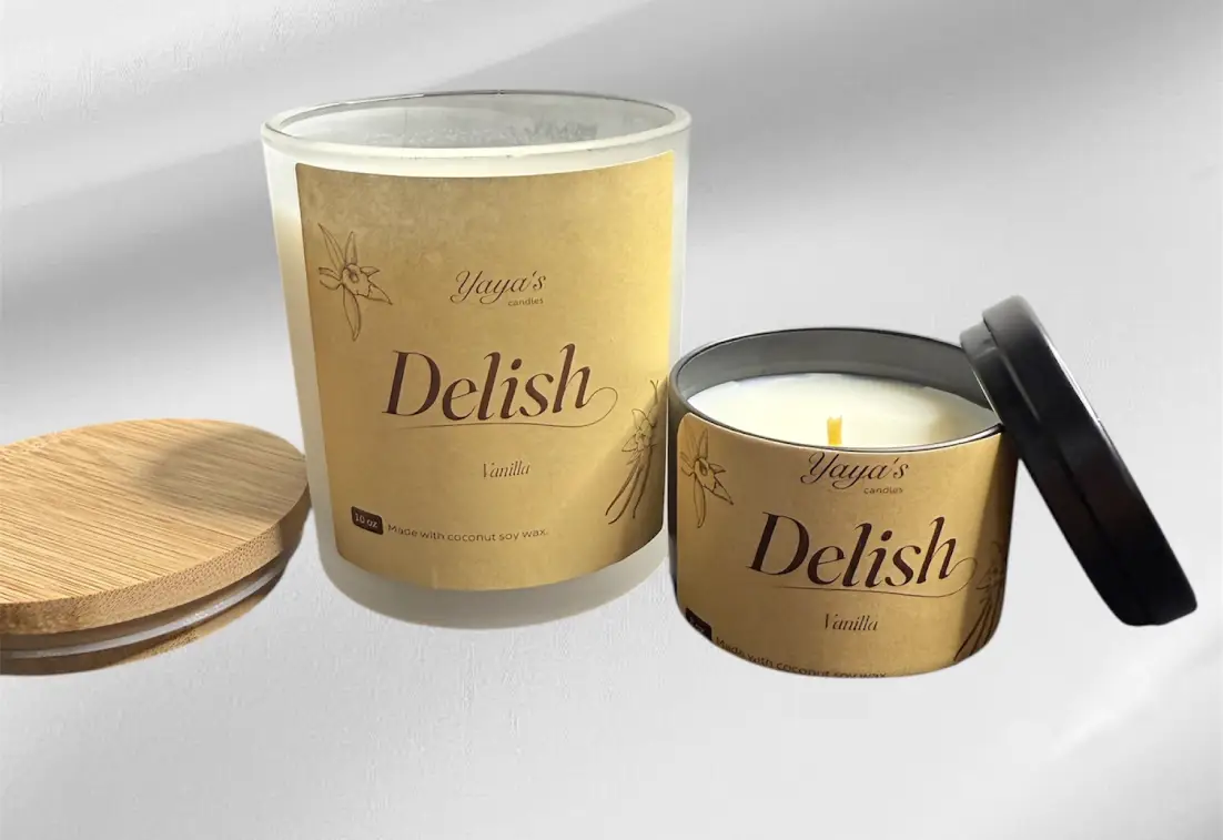vanilla-product-images-for-front-end Two vanilla-scented candles from Yaya's Candles: a clear jar and a black tin, both with earthy labels and a bamboo lid.