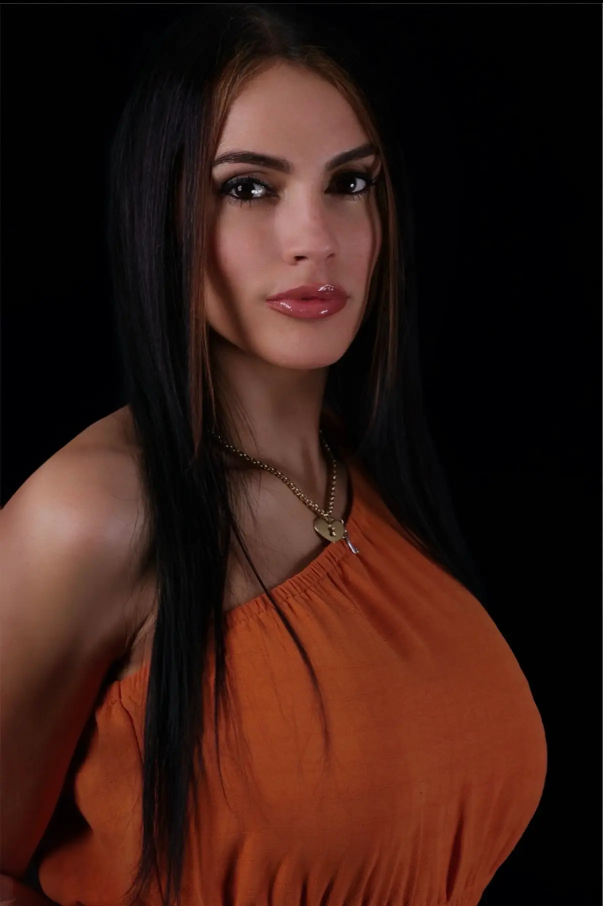 A woman with long, straight black hair wearing an orange off-shoulder top stands against a dark background, exuding confidence.